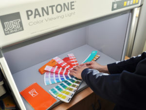 Comparing, visually measuring and recording our range of colour sign vinyls against Pantone colours in our Pantone Colour Booth.
