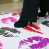 JT 8300 WM-RT Dot Floors printed with a lipstick kiss design in bright pinks, reds and other brighth shades is situated on a lobby floor and can be seen being walked over by a lady wearing high heeled shoes.