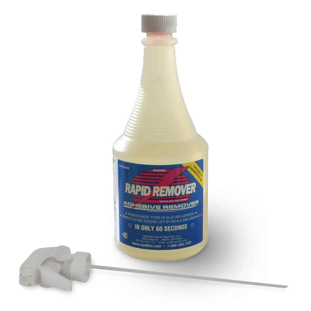 RAPIDREMOVER pale lemon colour liquid for removal of graphics adhesives, in its' 946ml bottle which has a corrugated neck for easier gripping. The bottle has it's screw cap on the lid rather than having the spray nozzle option inserted into the neck of the bottle. The white scree-on spray nozzle lays at the bottles feet.