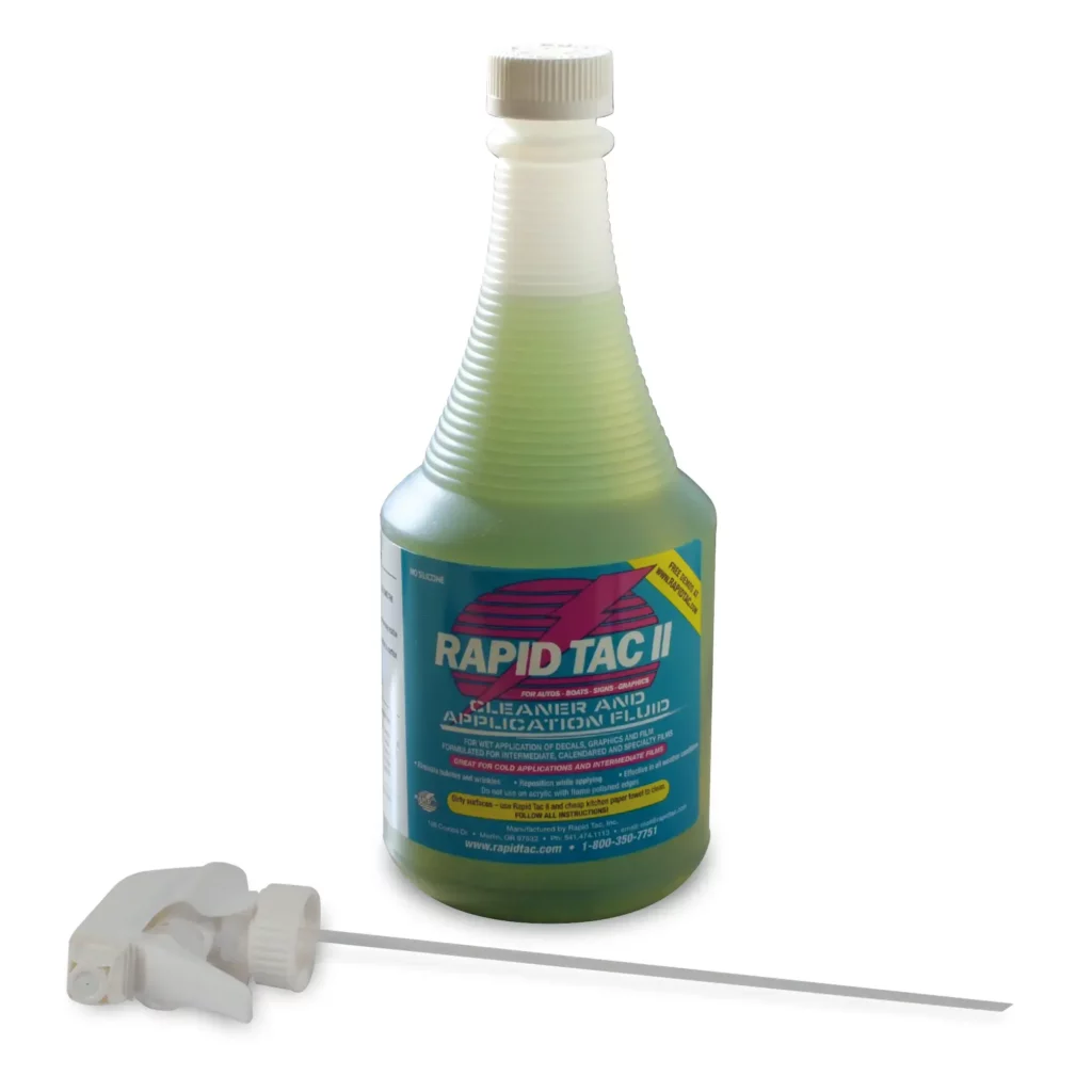 RAPIDTAC II green liquid for application of graphics onto windows and the like, is in its' 946ml bottle which has a corrugated neck for easier gripping. The bottle has it's screw cap on the top rather than having the spray nozzle inserted. The screw-cap trigger spray mechanism is lying at the foot of the bottle of fluid prior to inserting and replacing the screw on bottle cap.