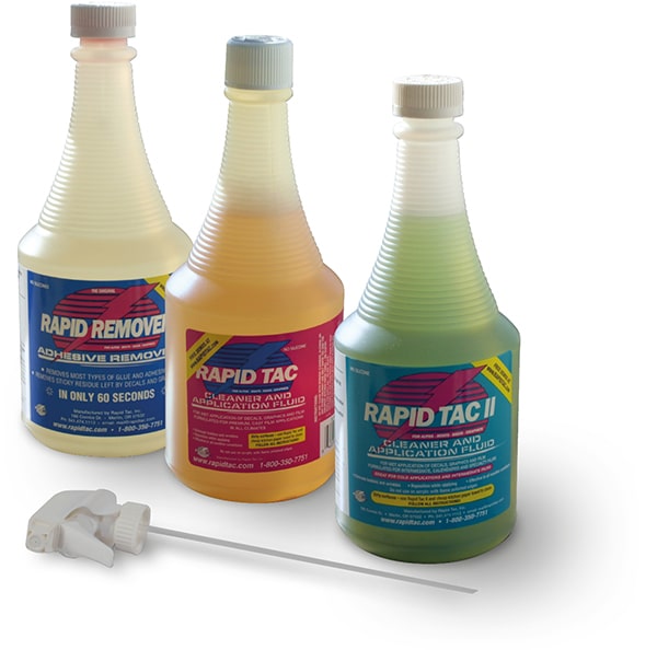 A group photo of the 3 x application fluids from RAPIDTAC; 1x adhesive remover and 2 x sign application fluids. From left to right: pale lemon coloured RAPIDTAC Adhesive Remover fluid, pink coloured RAPIDTAC Original sign vinyl application fluid and RAPIDTAC II light green coloured application fluid with the white sprayer nozzle laid out in front for inserting into each of the bottle types.
