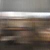 RG6 quarter-inch reeded glass line pattern decorative window film is pictured applied to a clear glass window with the shallow, subtle lens effect of the film providing a ribbed effect that bends light comgin through the window, providing decorative style and privacy to the window area.