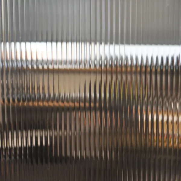 RG6 quarter-inch reeded glass line pattern decorative window film is pictured applied to a clear glass window with the shallow, subtle lens effect of the film providing a ribbed effect that bends light comgin through the window, providing decorative style and privacy to the window area.
