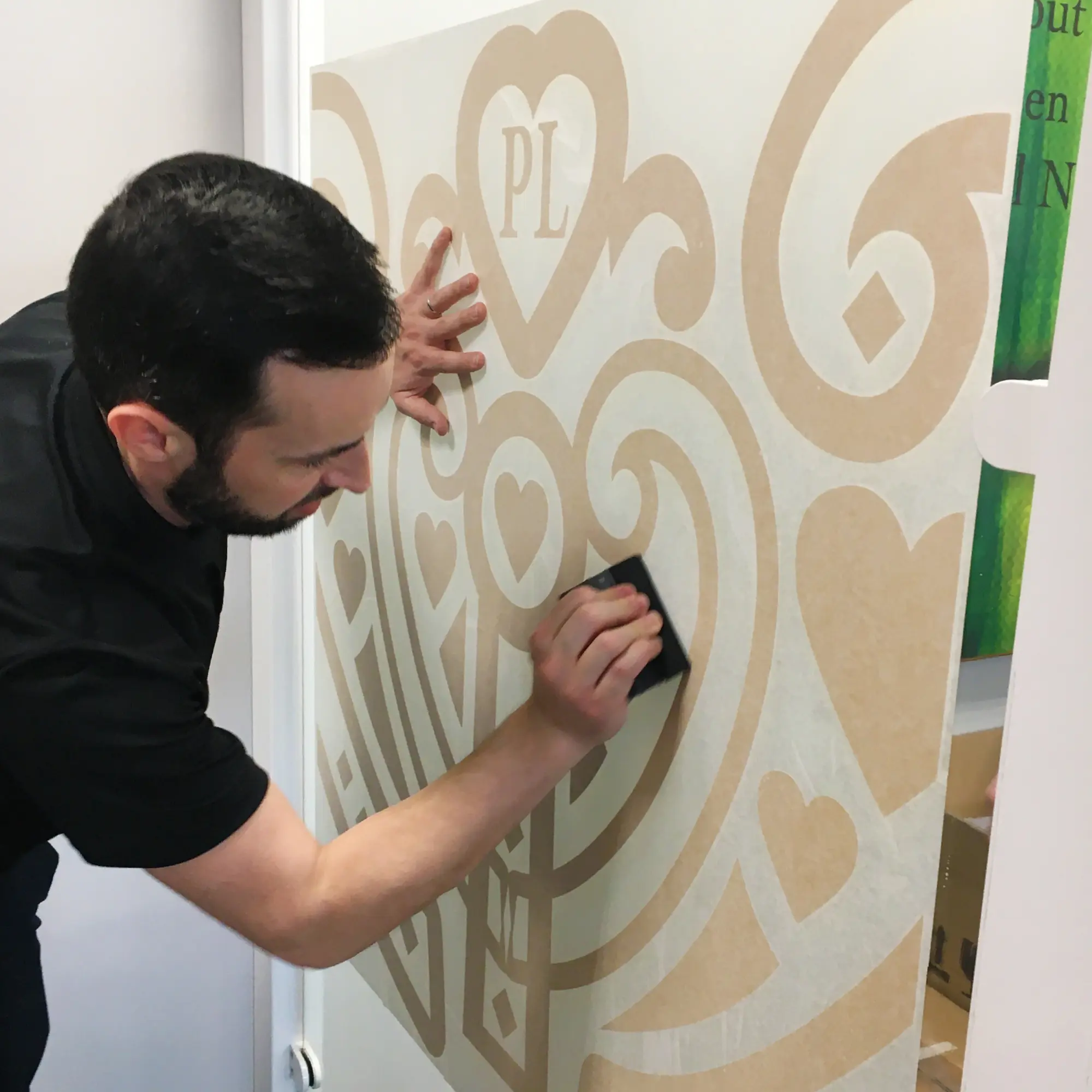 RTape Conform 4075 RLA graphics transfer paper being used to position an intricatley patterned cut-vinyl self-adhesive film onto a window.