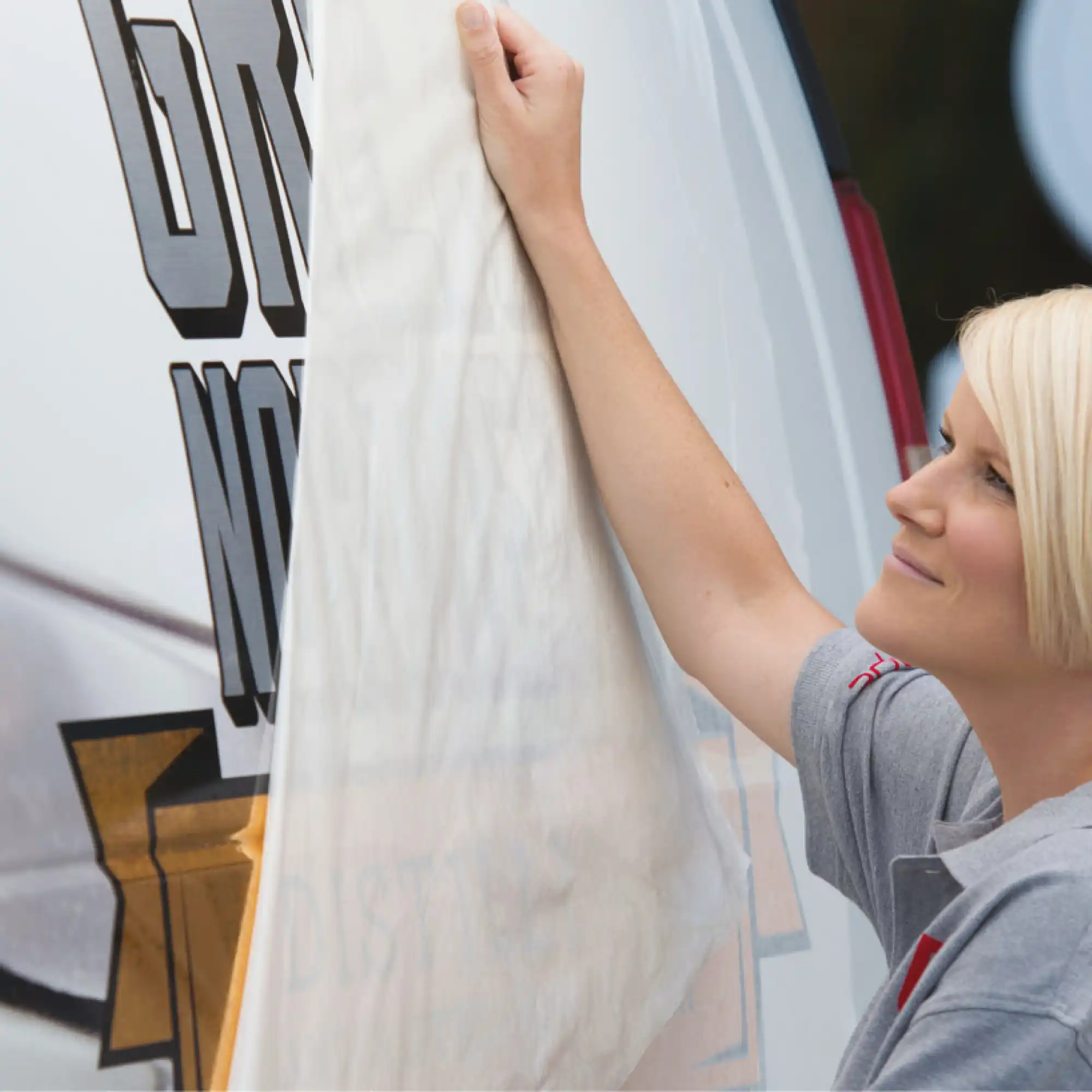 RTape Conform graphics application paper being pulled away from the self-adhesive vinyl graphic branding imagery which has been positioned and applied using the transfer paper onto the side of a company vehicle.