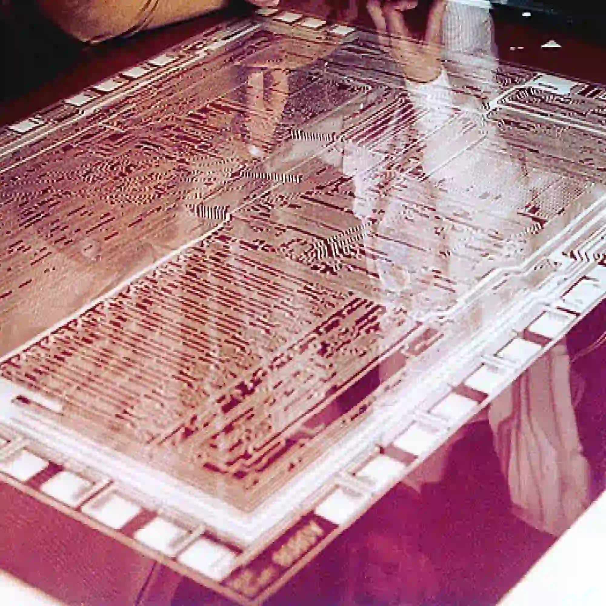 Rubylith stencil film with release liner still attached laid out on a lightbox with an intricate cut-out design weeded out to allow light to shine though from beneath.