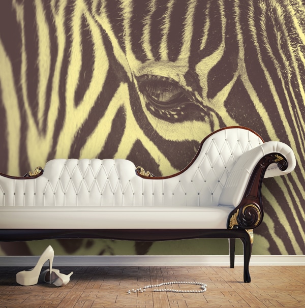Sihl 2512 design2wall custom printed wallpaper on an interior living room wall with a couch in front of a tan brown and light creamy yellow toned print of zebra animal stripes.