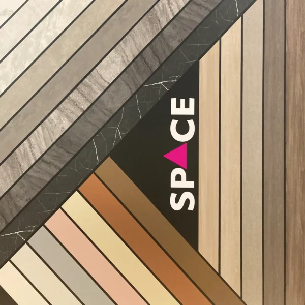 The decorative wall in the SPACE Interior Films training and demo area at All Print Supplies in Slough uses a small selection of self-adhesive interior films from the range of LX Hausys interior films to attractively showcase a few product choices with this wall display, including dark and light marble patterns, solid textured colours, woodgrain, leather, painted wood and more. Strips of dfferent films have been applied at 45 degree and 90 degree angles to each other rather like modern media centres, with a black vinyl background to accentuate out all the different complimentary colours and textures used.