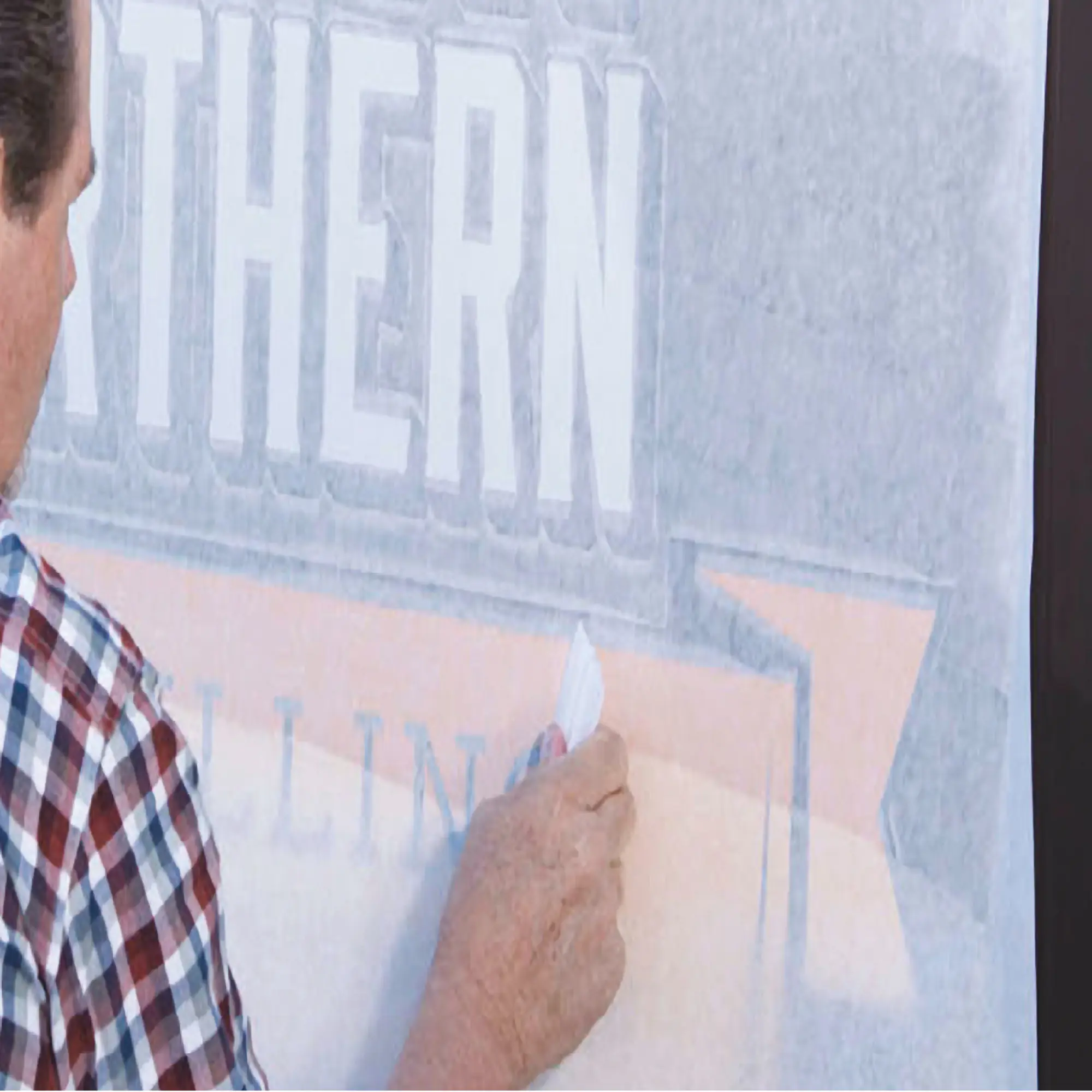 Squeegeeing a UV printed self-adhesive vinyl graphic onto a window with RTape Conform 4760 RLA application tape to transfer the image onto the final application surface.