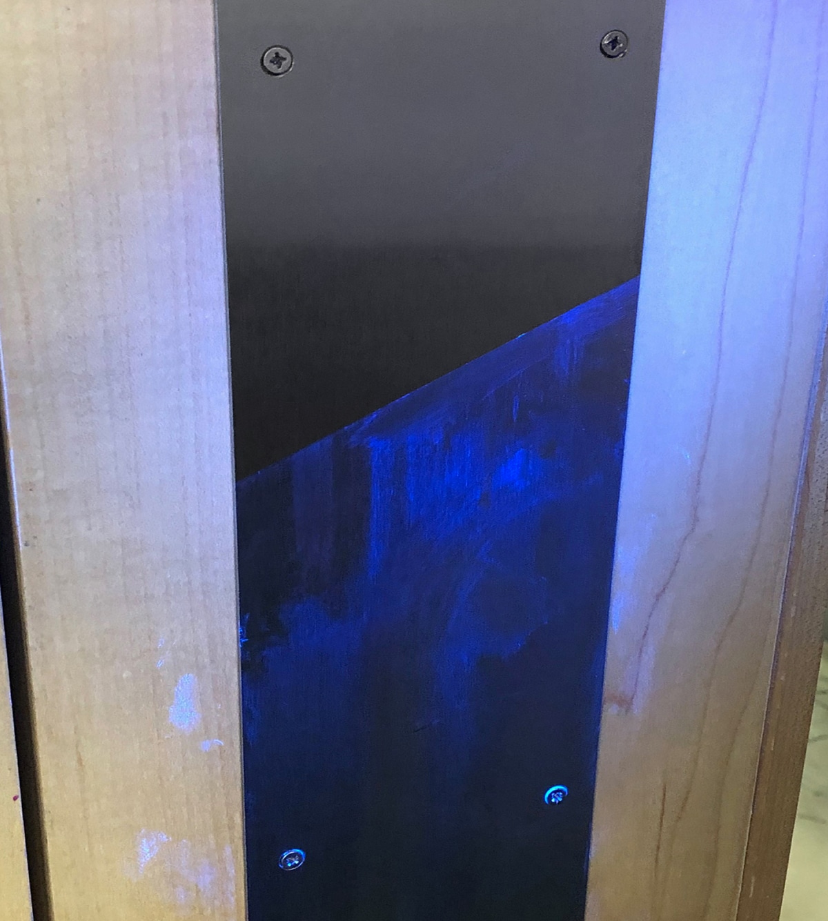 A door plate shown under UV light: T36-P laminate on the top after having been wiped clean. Underneath is unlaminated... the bacteria left on the surface after a wipe down is evident.