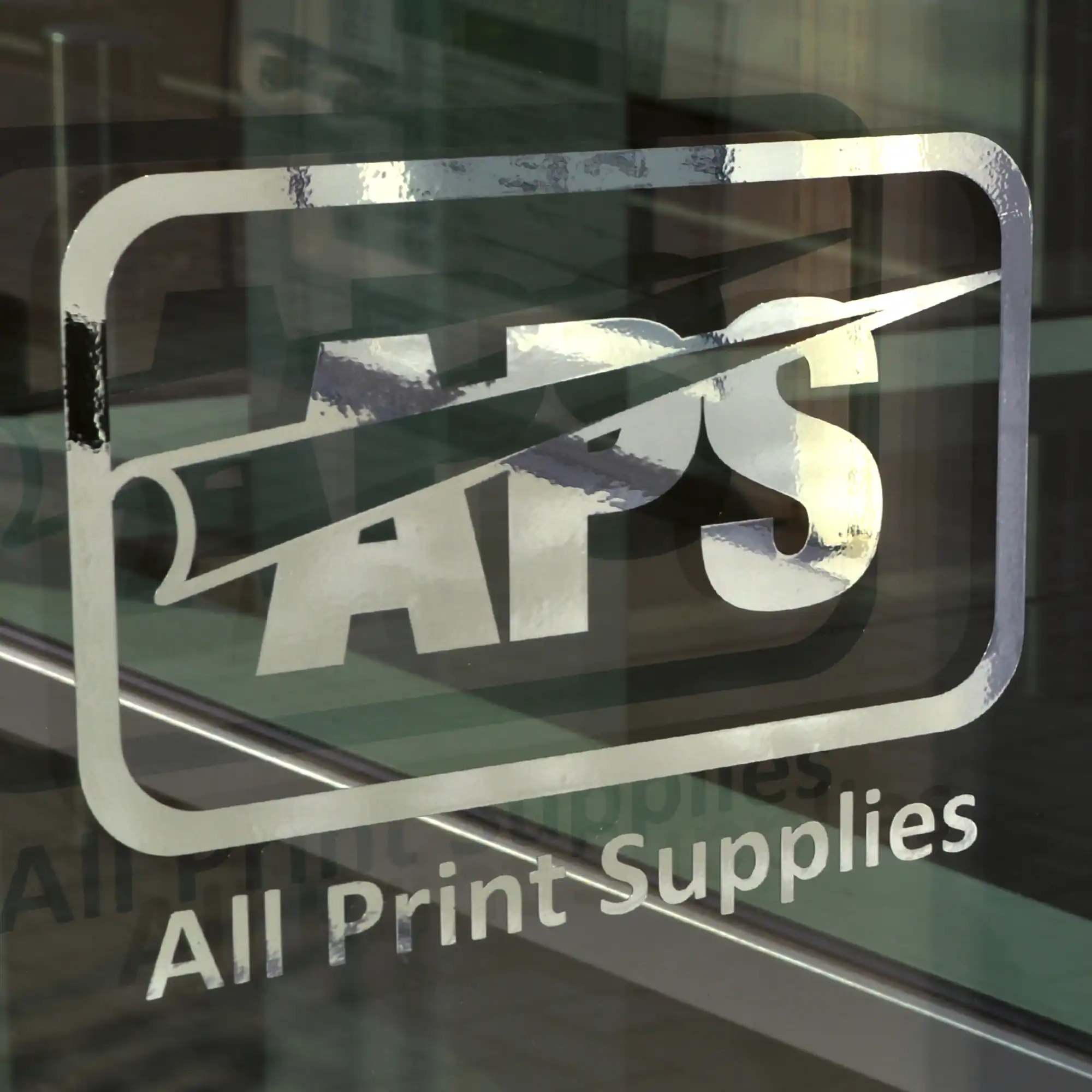 NU-COAT T60-P bright two-way silver self-adhesive metallised graphics film is pictured here plotter-cut into the APS company logo and is applied to an external window as decoration and building signage.