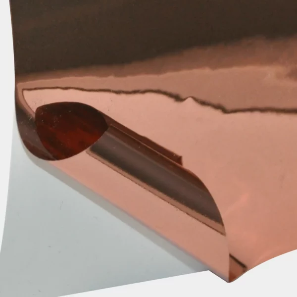 T72-P Bright Two-Way Rose Gold self-adhesive metallised graphics vinyl with the face film pulled back to reveal the carrier-liner behind showing both sides of the film look identical on the face and on the back (adhesive side) meaning it can be used as a two-way viewable window film.