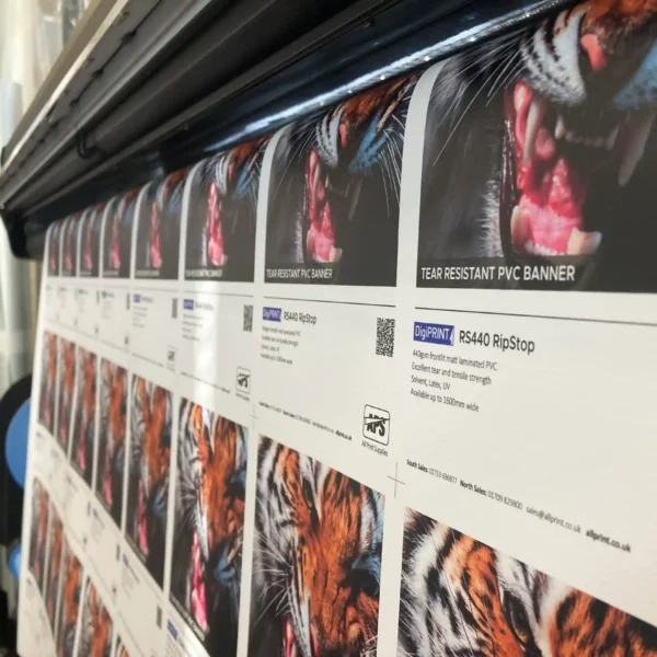 Tear resistant, high strength scrim banner material, RipStop RS440 being printed on an HP Latex wide format digital printer with all the A5 product sample images imposed across the full width and drop of the roll media as it hangs from the front of the printing machine.