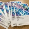 DigiPRINT TSSP225 satin photo paper in a stacked pile of printed A5 size promotional leaflets / sample prints.