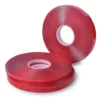 Clear double-sided ultra high bond sign tape, UHB-C-10F, shown in reeled rolls in the three different sizes, two of the reel widths are on their side, horizontally stacked on top of each other, and the third reel is offset to the side standing upright on it's short edge.