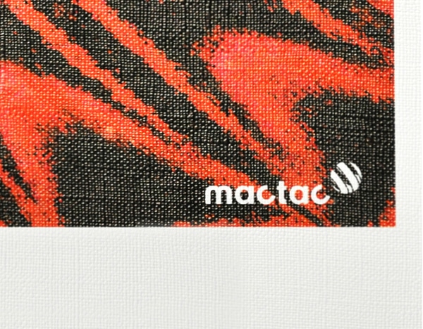 WW Canvas satin white self-adhesive textured wall decoration vinyl is shown in close up detailing the textile pattern on the printed and unprinted areas of a sample of the material. The printed part of the sample shows the product brand group image of a deep red, orange and black butterfly wing with the Mactac brand logo in the bottom right corner. At the very bottom of the image you can see the pattern of the unprinted satin white canvas texture of the base material.