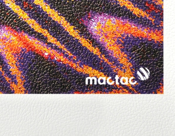 WW Leather textured self-adhesive wall vinyl is shown in close up detailing the printed and unprinted areas of a sample of the material with the leather vein pattern of the embossed print media. The printed part of the sample shows the product brand group image of a bright red, yellow and purple butterfly wing with the Mactac brand logo in the bottom right corner. At the very bottom of the image you can see the pattern of the unprinted satin white base material.