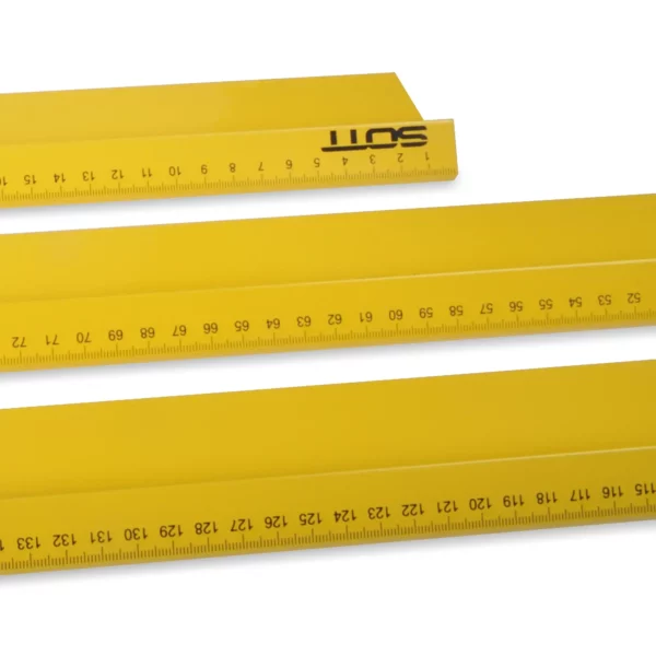 Bright yellow safety rulers laid one in front of the other ranging from small in the background to largest in the foreground in 3 sizes (500mm, 1000mm & 1500mm) - all featuring the significantly raised lip for finger protection along the cutting edge which is facing towards the camera, with a focus on the measurements.